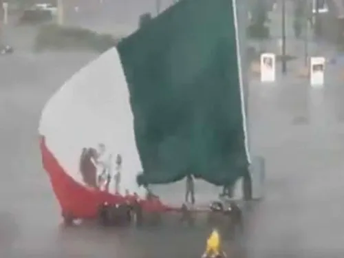 Soldados y civiles luchan contra el viento y bajan la bandera