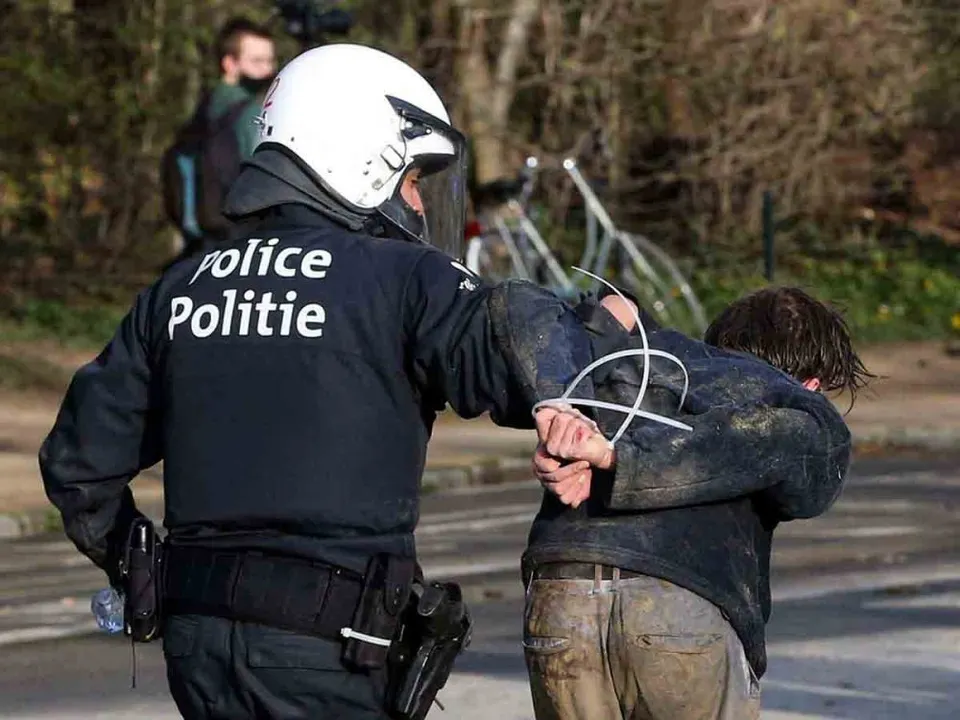 A Belgian police officer arrest a demonstrator at the Bois de la Cambre parc, in Brussels, on April 1, 2021 during a unauthorised rally, for a fake concert announced on social media as an April Fool’s Day prank. – Police on horseback and using a water cannon charged a crowd of thousands of people gathered in a Brussels park for a fake concert announced on social media as an April Fool’s Day prank. AFP journalists at the scene saw at least one police officer injured and several people in the crowd arrested. (Photo by François WALSCHAERTS / AFP)