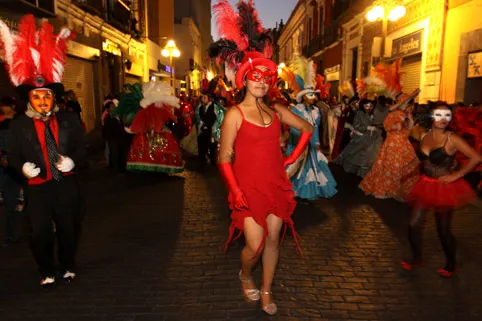 Colorido desfile de Huehues en el centro histórico de Puebla