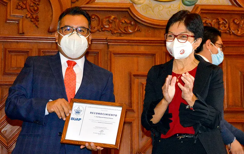 José Manuel Alonso, secretario general de la BUAP, con su reconocimiento, acompañado por la rectora Lilia Cedillo. Foto: Especial