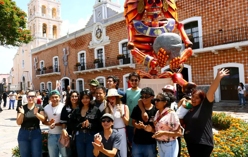 Los artistas participantes en el Valle de Catrinas 2026 posan ante la escultura de Tonatiuh. Foto: Raúl R. de la Rosa / Reto diario