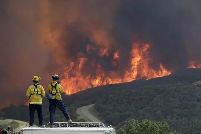 Varios bomberos observan el avance del fuego en California